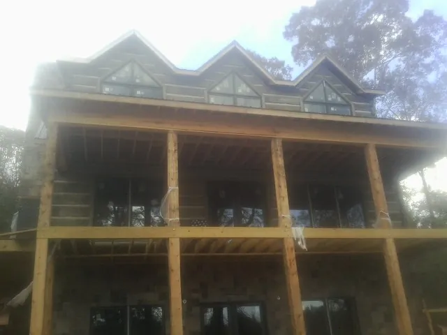 Dormers and porch framing on a large log home under construction — Roof Coating work by our crew in Paris